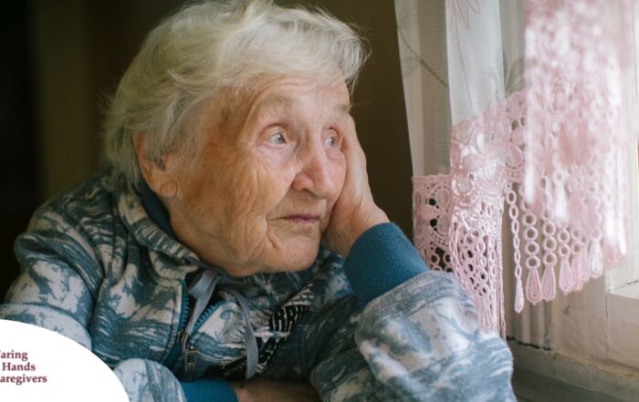 An older woman peacefully looks out of the window while the sun is still up, representing what can happen with sundowning.